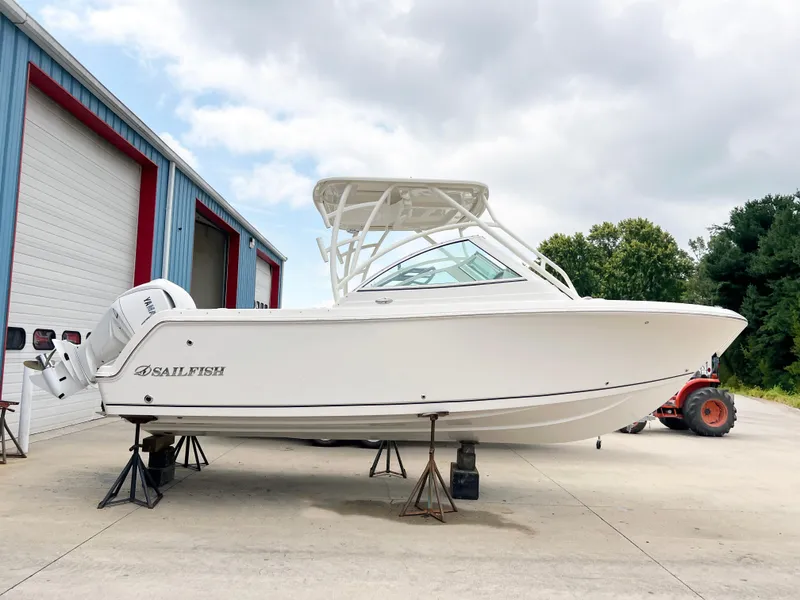 The Image of 2025 Sailfish 245 DC boat on stands outside a garage, side view. - 0