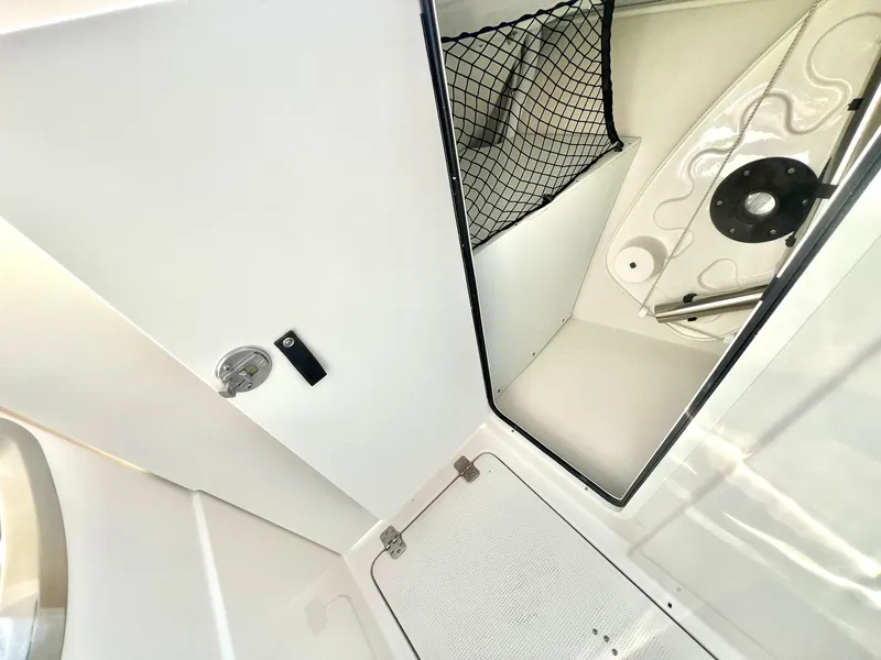 Slide: The Image of 2025 Sailfish 245 DC interior storage compartment with netting and hatch. - 19