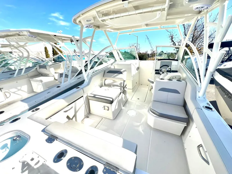 Slide: The Image of 2025 Sailfish 245 DC boat interior with seating and helm, under a clear blue sky. - 2