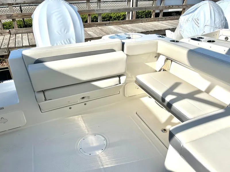 Slide: The Image of 2025 Sailfish 245 DC boat interior with white seating and deck, docked outdoors. - 8