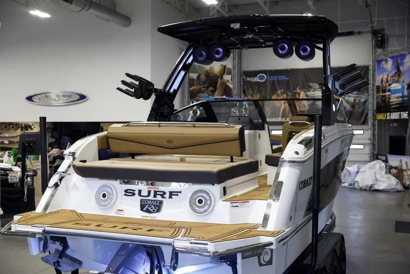 Slide: The Image of 2025 Cobalt R8 Surf boat in showroom, rear view with seating and speakers. - 8