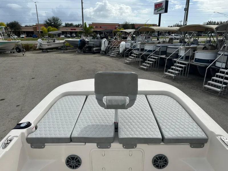 Slide: The Image of 2025 Carolina Skiff 21 LS boat with cushioned seating, parked in a marina. - 9