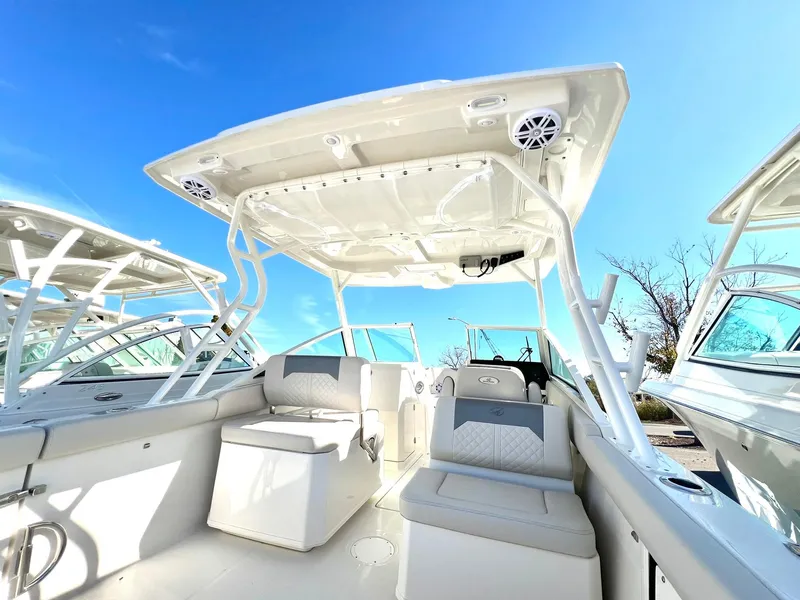 Slide: The Image of 2025 Sailfish 276 DC boat interior with seating and canopy under clear blue sky. - 15