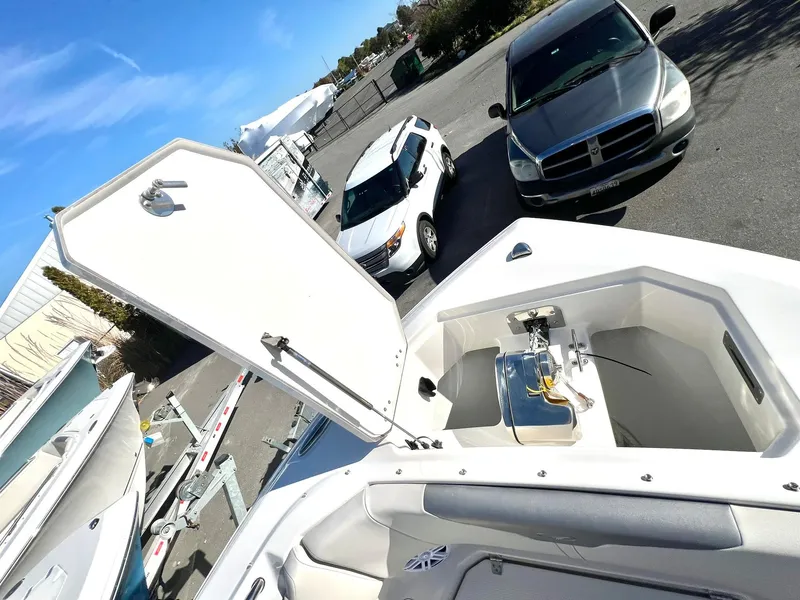 Slide: The Image of 2025 Sailfish 276 DC boat with open storage compartment, parked near vehicles. - 3