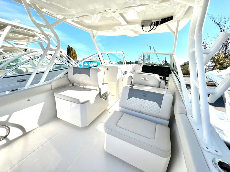 Slide: The Image of 2025 Sailfish 276 DC boat interior with modern seating and helm, under clear blue sky. - 40