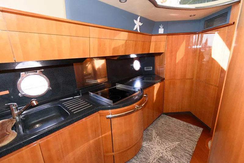 Slide: The Image of Luxurious kitchen interior of 2005 Azimut 50 Flybridge yacht with wood cabinetry and porthole windows. - 27