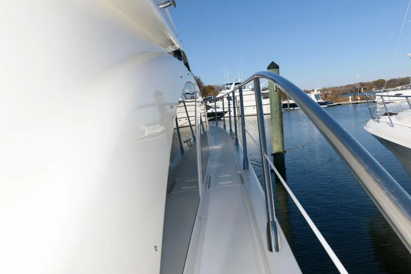 Slide: The Image of 2005 Azimut 50 Flybridge yacht docked, showcasing sleek side deck and railing. - 7