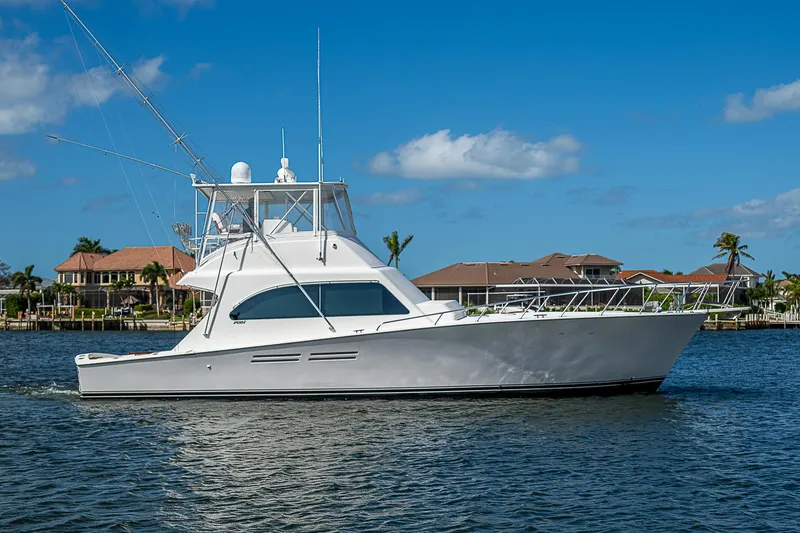 Slide: The Image of 1999 Post 50 Convertible yacht cruising on a sunny day near waterfront homes. - 3