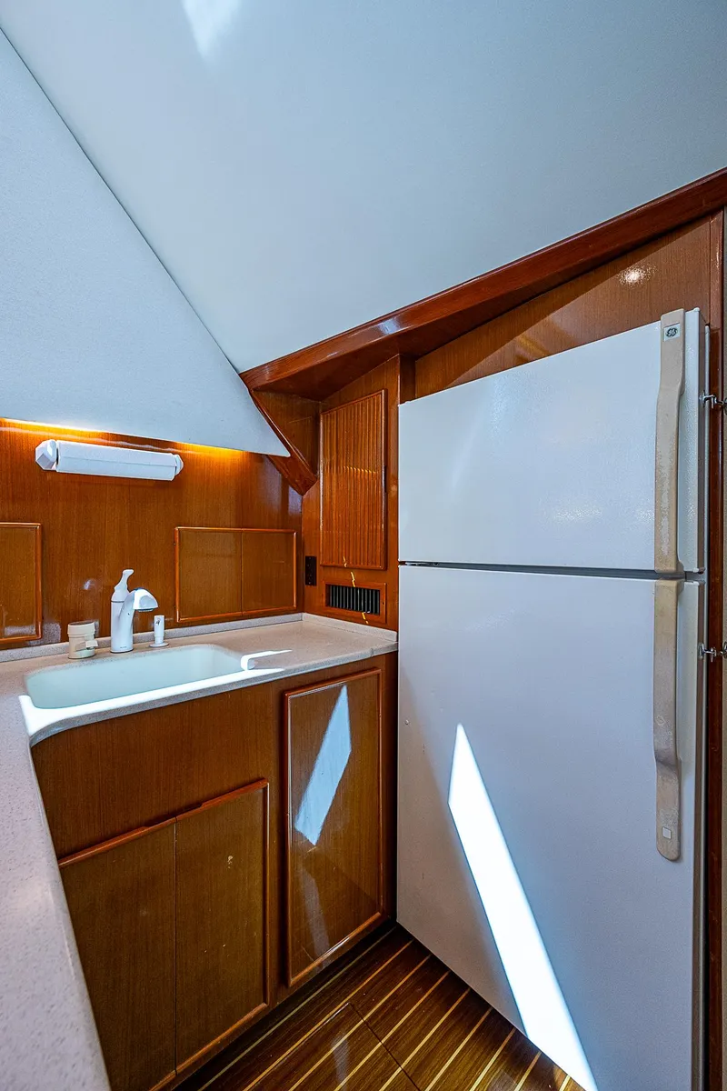 Slide: The Image of 1999 Post 50 Convertible yacht kitchen with wooden cabinets and white appliances. - 50