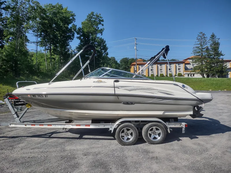 The Image of 2006 Sea Ray 200 Sundeck boat on trailer, parked outdoors on a sunny day. - 0