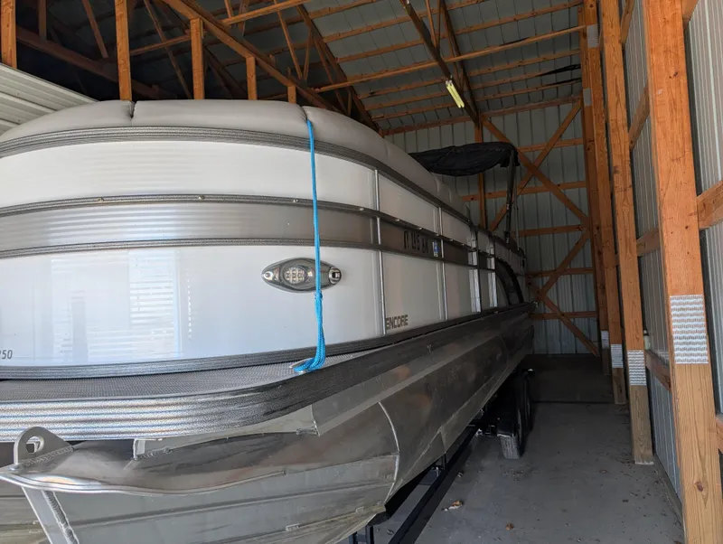 Slide: The Image of 2019 Manitou 25 Encore SE pontoon boat stored in a wooden shed. - 12