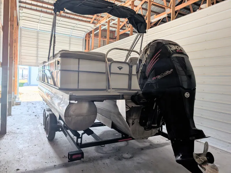 Slide: The Image of 2019 Manitou 25 Encore SE pontoon boat with outboard motor in storage. - 14