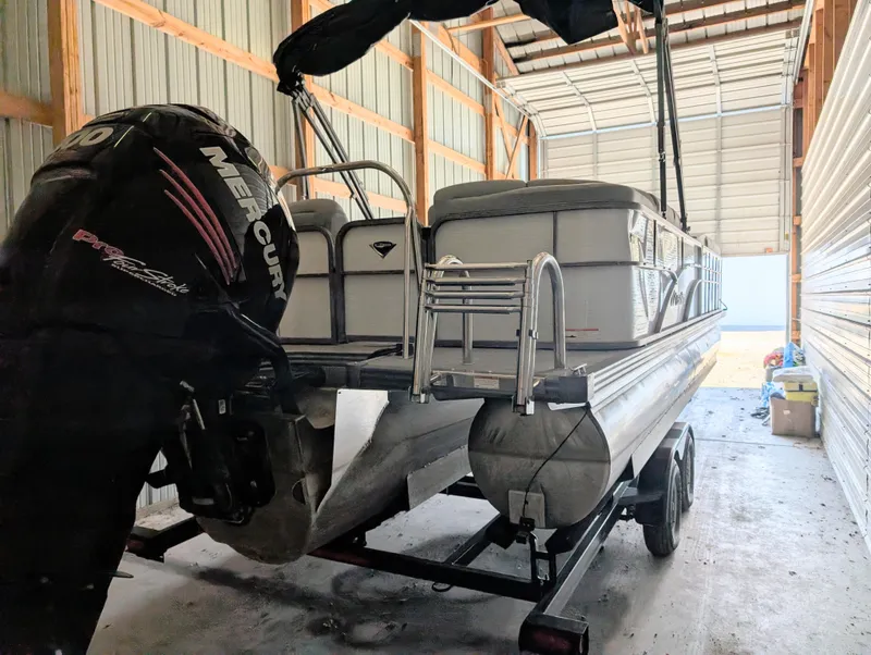 Slide: The Image of 2019 Manitou 25 Encore SE pontoon boat with Mercury engine in storage. - 15