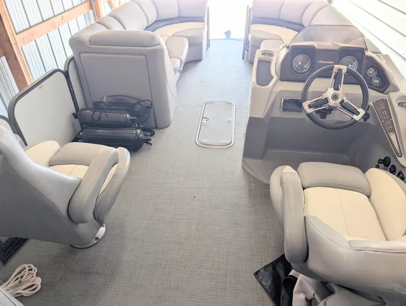 Slide: The Image of 2019 Manitou 25 Encore SE pontoon boat interior with plush seating and modern steering console. - 22