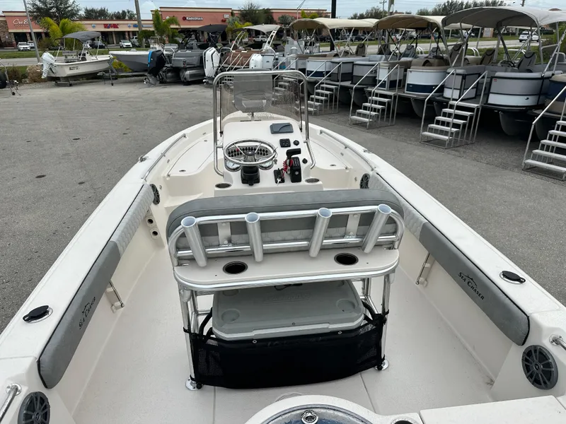 Slide: The Image of 2025 Sea Chaser 21 LX boat interior with seating and console, docked at marina. - 17