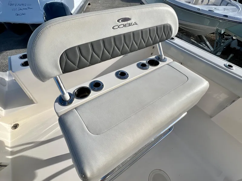 Slide: The Image of 2023 Cobia 220 CC boat seat with cup holders and logo. - 11