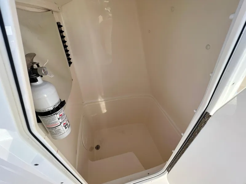 Slide: The Image of 2023 Cobia 220 CC storage compartment with fire extinguisher. - 26