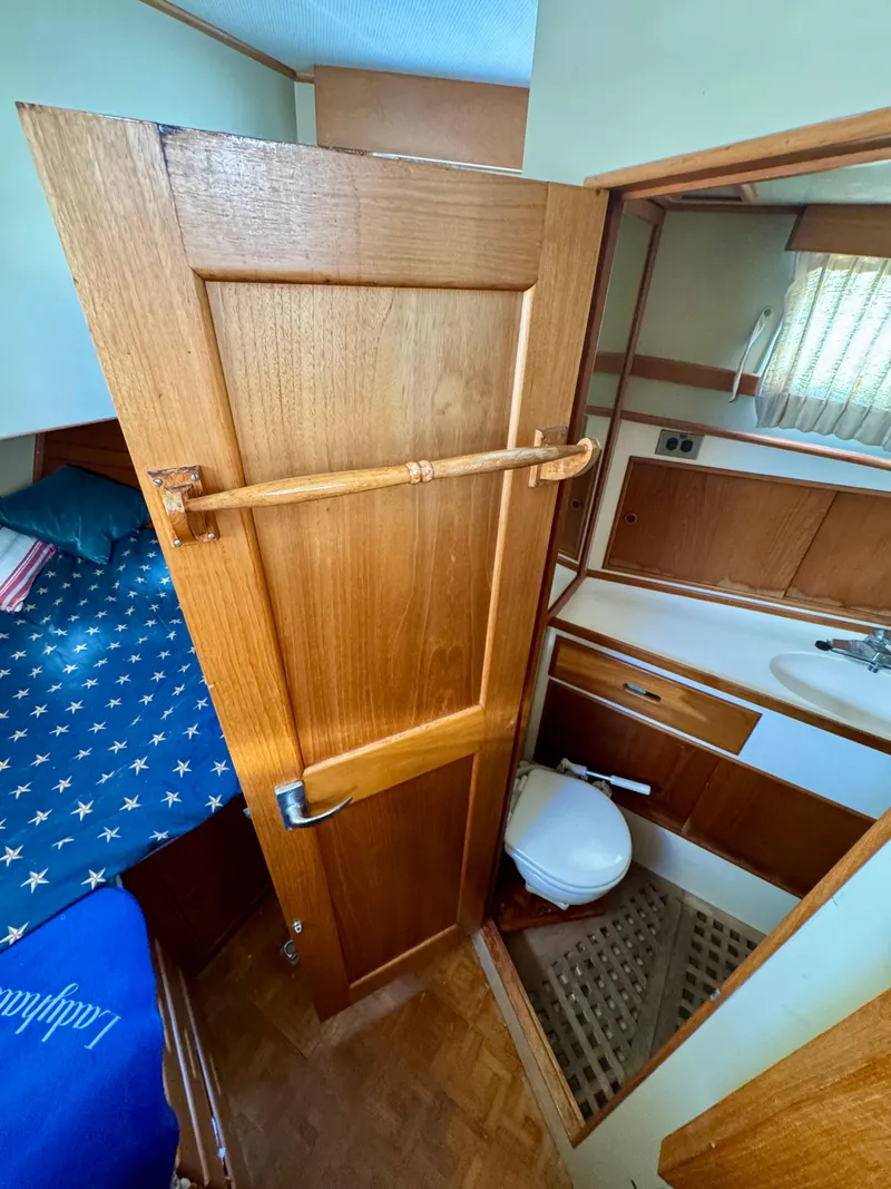 Slide: The Image of 1979 Grand Banks Classic boat interior with wooden door, cozy cabin, and compact bathroom. - 10