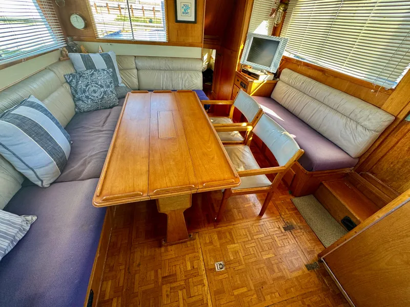 Slide: The Image of 1979 Grand Banks Classic yacht interior with wooden table, cushioned seating, and a small TV. - 27