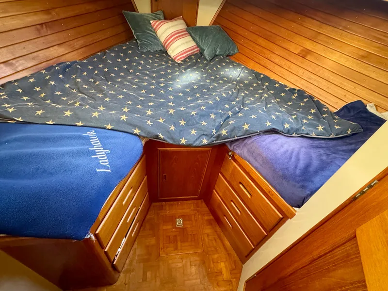 Slide: The Image of Cozy 1979 Grand Banks Classic cabin with star-patterned bedding and wooden storage drawers. - 5