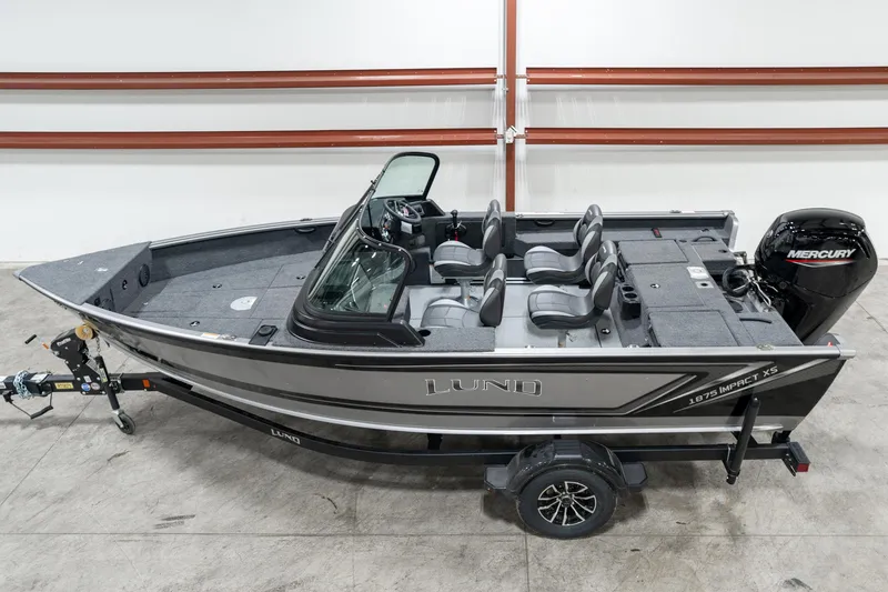 Slide: The Image of 2025 Lund 1875 Impact fishing boat with Mercury engine, parked indoors. - 1