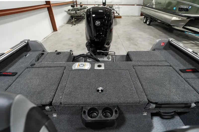 Slide: The Image of 2025 Lund 1875 Impact boat interior with motor, storage compartments, and cup holders in a garage. - 15