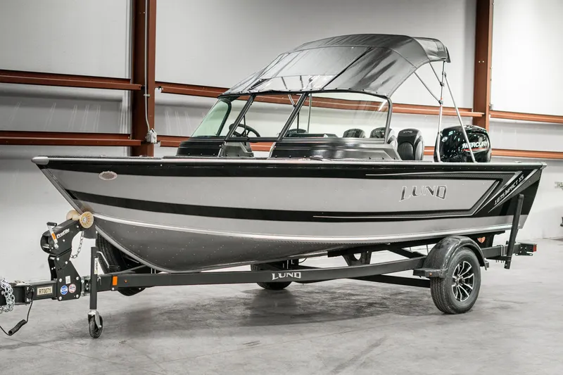 Slide: The Image of 2025 Lund 1875 Impact boat on trailer in indoor setting. - 2