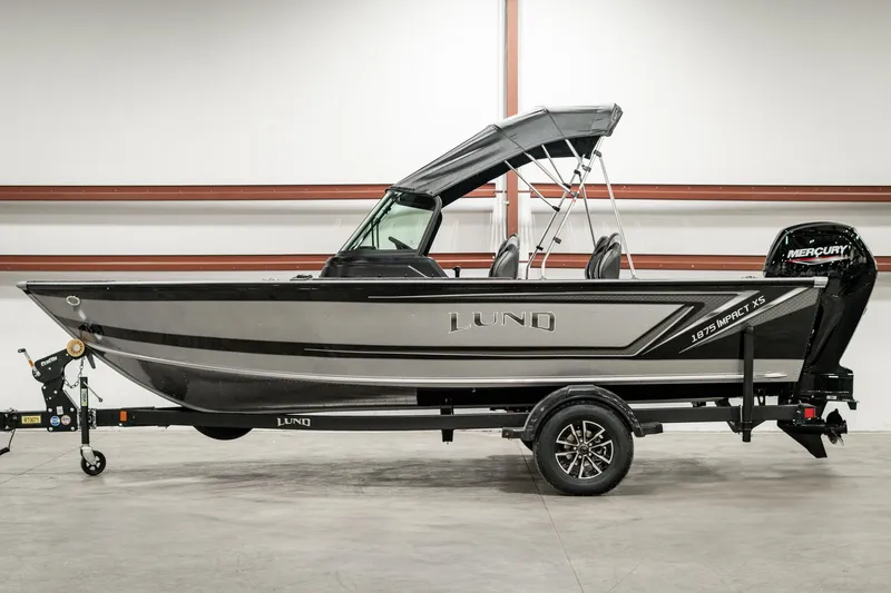 Slide: The Image of 2025 Lund 1875 Impact boat with trailer in a showroom setting. - 5