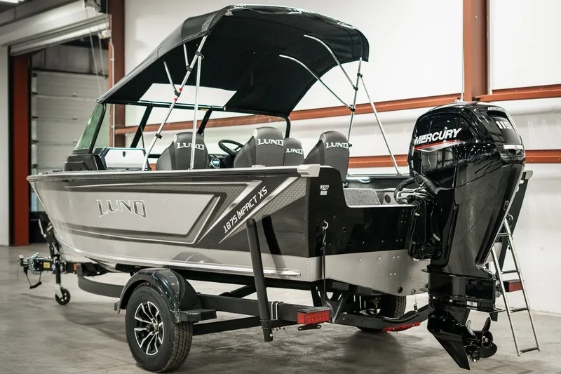 Slide: The Image of 2025 Lund 1875 Impact boat with Mercury outboard motor in a garage setting. - 6