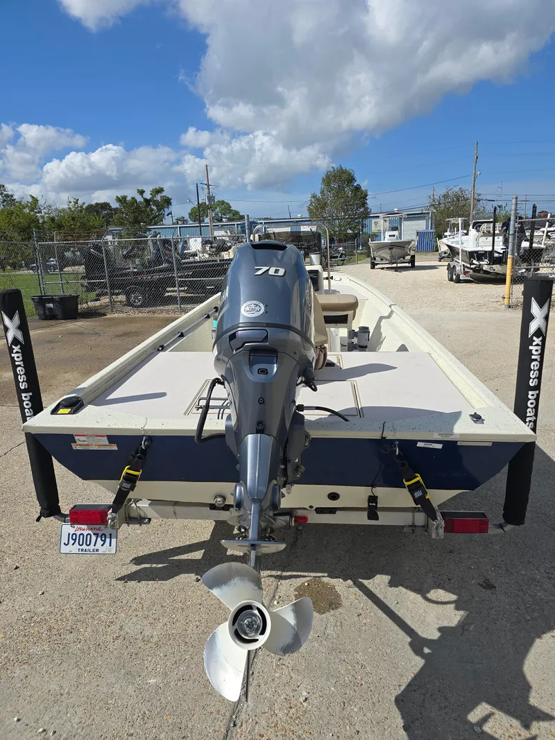 Slide: The Image of 2020 Xpress XP18CC boat with outboard motor, parked outdoors under a cloudy sky. - 8