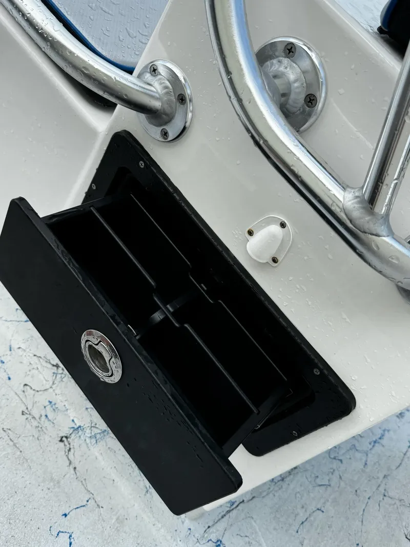 Slide: The Image of 2024 Mowdy 25 Catamaran boat detail with open storage compartment and metal railing. - 23