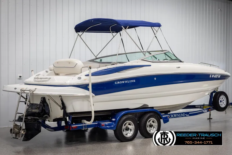 Slide: The Image of 2008 Crownline 240 EX boat with blue accents on a trailer in a showroom. - 6