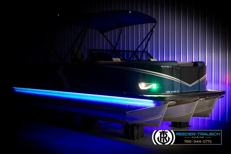Slide: The Image of 2025 Avalon LSZ ELW pontoon boat with blue LED lights in a dimly lit showroom. - 4