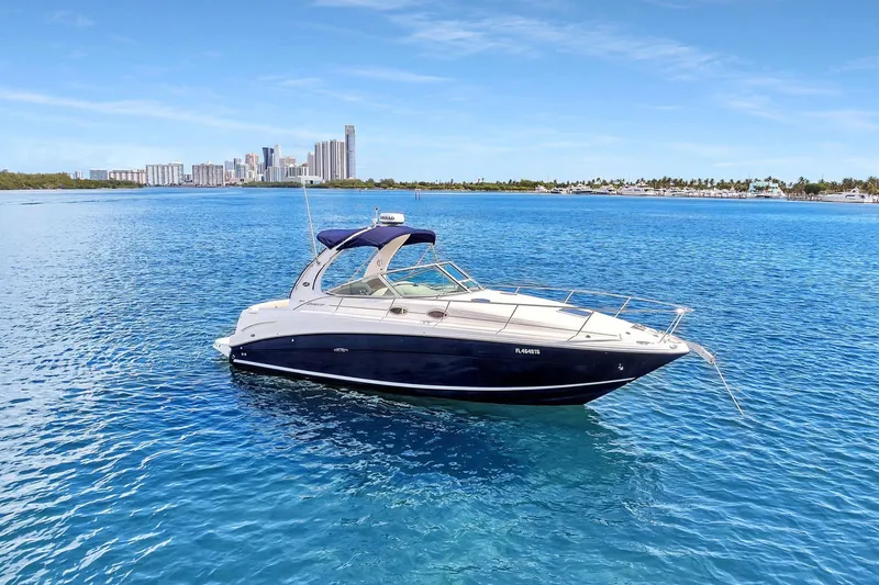 Slide: The Image of 2006 Sea Ray 300 Sundancer yacht on clear blue water with city skyline in background. - 0