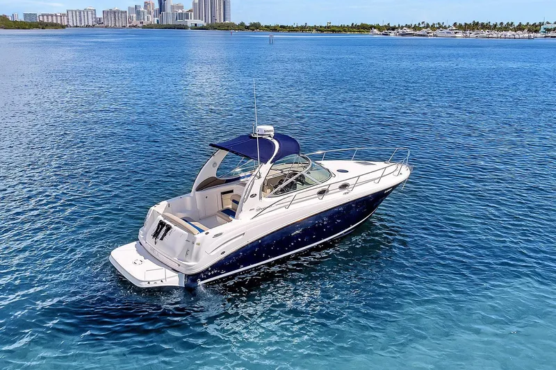 Slide: The Image of 2006 Sea Ray 300 Sundancer yacht on clear blue water with city skyline in background. - 1
