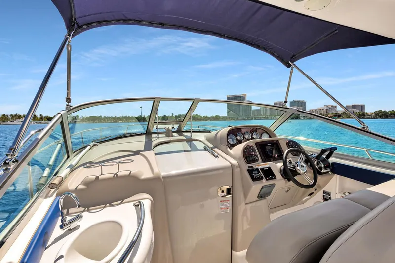 Slide: The Image of 2006 Sea Ray 300 Sundancer cockpit with steering wheel, sink, and canopy on a sunny day. - 3