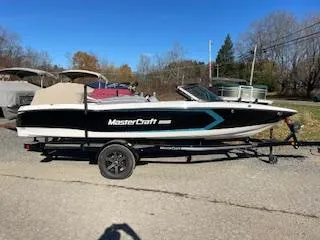 Slide: The Image of 2024 MasterCraft ProStar boat on trailer, parked outdoors on a sunny day. - 0