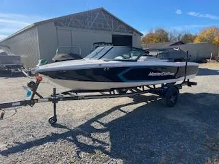 Slide: The Image of 2024 MasterCraft ProStar boat on trailer, parked outdoors near a barn. - 1