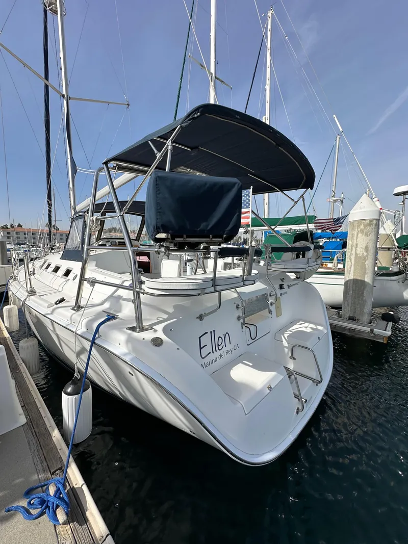 Slide: The Image of 2008 Hunter 38 sailboat docked at marina, featuring a spacious deck and canopy. - 10