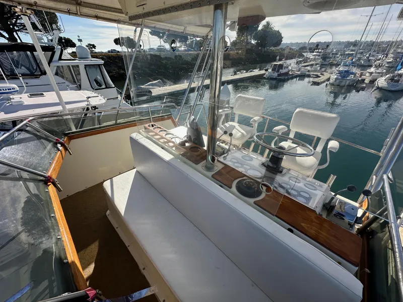 Slide: The Image of 1985 Egg Harbor 33 Sedan boat interior with seating and helm, docked in a marina. - 16
