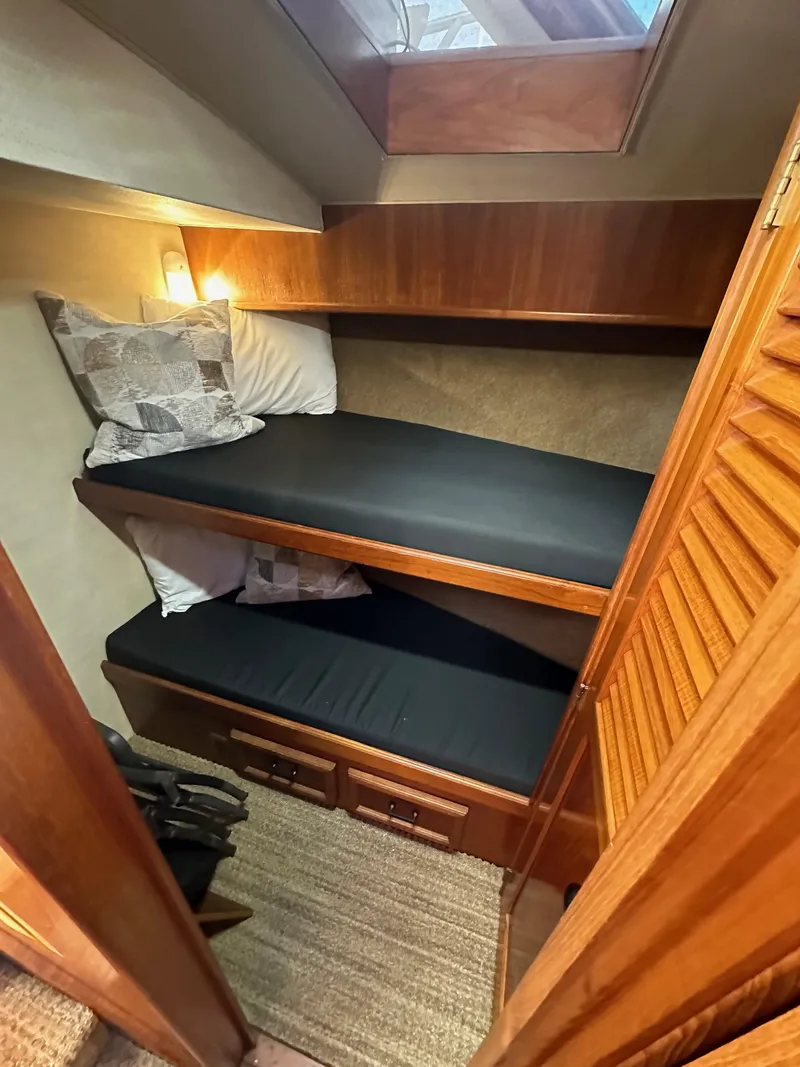 Slide: The Image of 1985 Egg Harbor 33 Sedan cabin with wooden bunk beds and cozy lighting. - 33