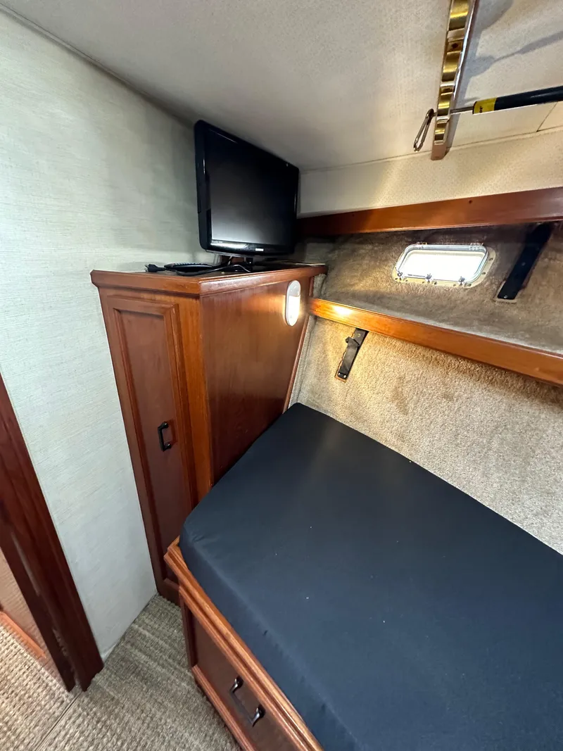 Slide: The Image of 1985 Egg Harbor 33 Sedan cabin interior with bed, TV, and wooden cabinetry. - 39
