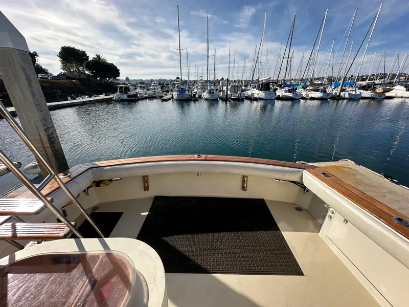 Slide: The Image of 1985 Egg Harbor 33 Sedan boat docked in a marina with sailboats in the background. - 47