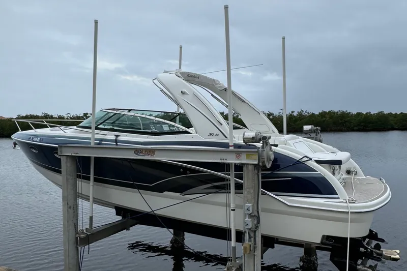 Slide: The Image of 2018 Formula 310SS boat on lift by the water, overcast sky. - 2