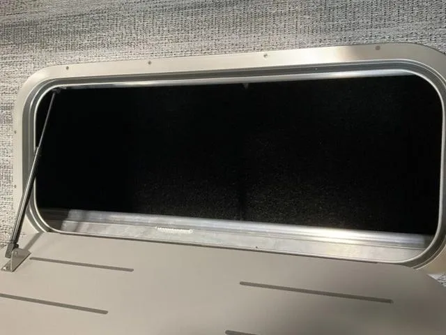 Slide: The Image of Storage compartment of 2025 Bennington 23 SL boat, open with metal frame and dark interior. - 9