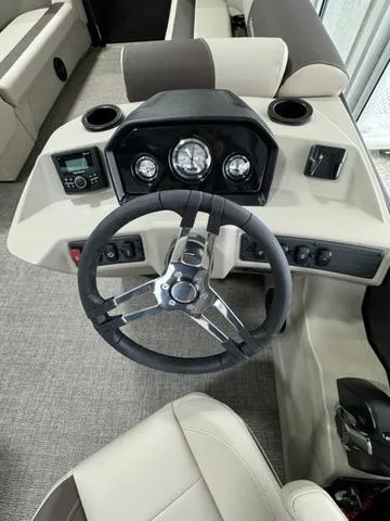 Slide: The Image of 2025 Bennington 23 SL pontoon boat in showroom, featuring sleek black design and beige seating. - 6