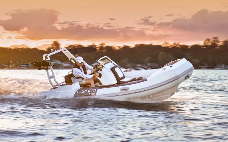 Slide: The Image of 2025 Highfield Velox 420 boat interior with steering console and seating in a warehouse setting. - 7