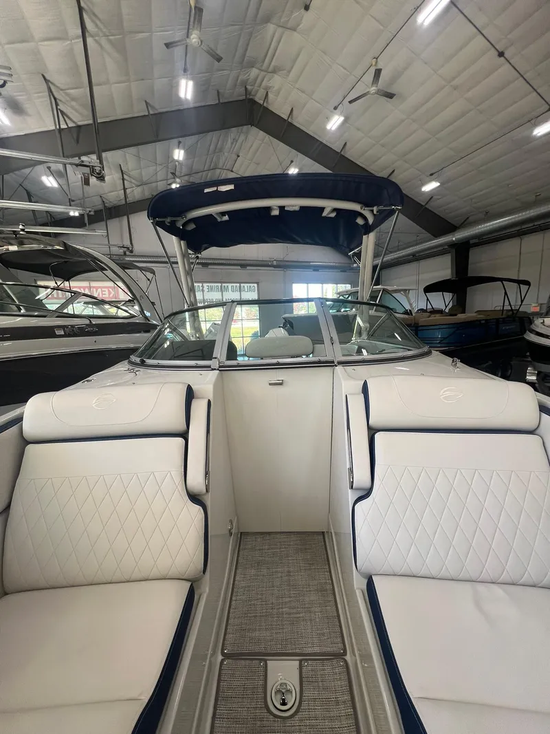 Slide: The Image of 2025 Crownline Eclipse E260 XS boat interior with white seating in a showroom. - 10