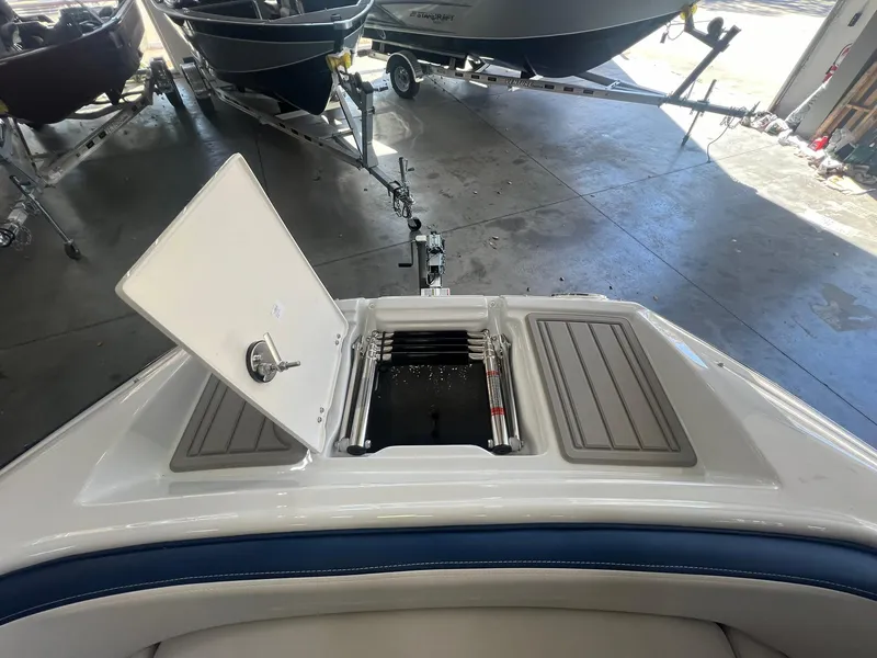 Slide: The Image of 2025 Crownline Eclipse E260 XS boat with open storage compartment in a showroom. - 11