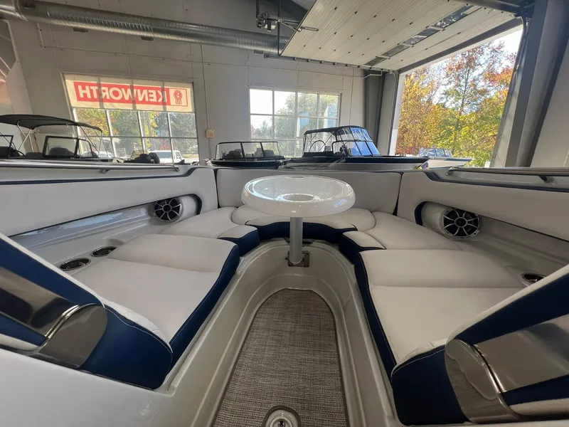 Slide: The Image of 2025 Crownline Eclipse E260 XS boat interior with seating and table in showroom. - 17